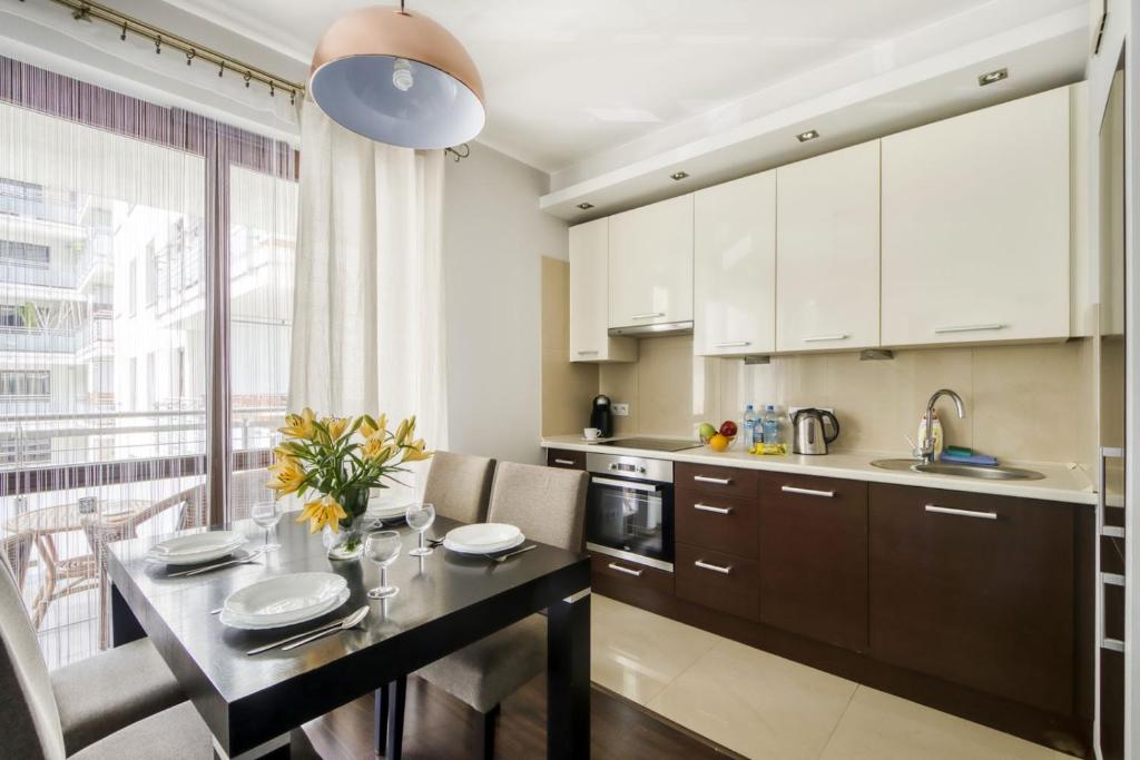 华沙MG Apartments Giełdowa的厨房配有白色橱柜和桌椅
