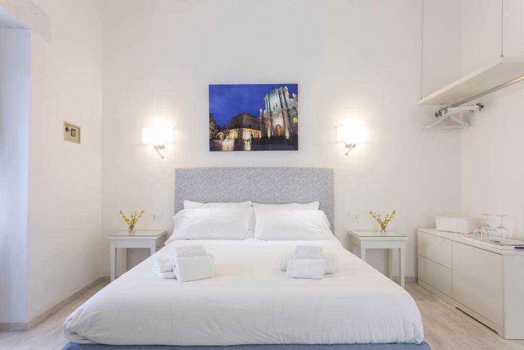 锡拉库扎Affittacamere Ortygia Inn Rooms con Terrazza sul Mare e Jacuzzi的白色卧室配有一张大白色床和两张桌子
