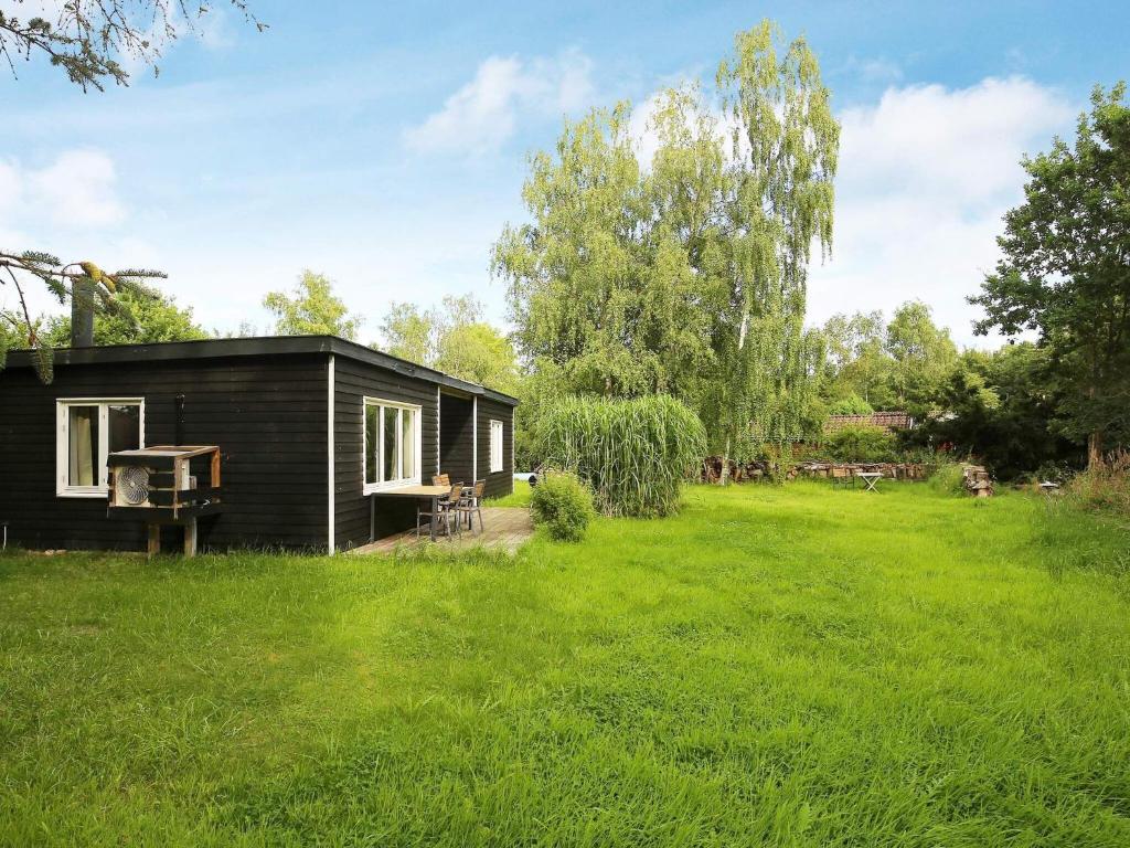 HornsvedTwo-Bedroom Holiday home in Jægerspris 1的草地庭院中的一个黑色小小屋