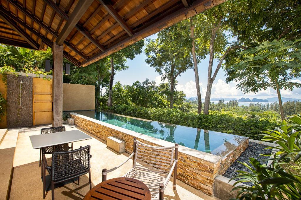 阁遥岛SAMSAM Yao Noi - ANDAMAN MAGIC & ART VILLAS的庭院中一个带椅子和桌子的游泳池