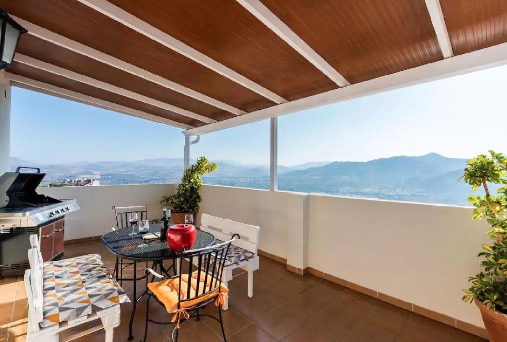 阿洛拉Ático Guadalhorce - Mirador privado con barbacoa y solárium的设有一个配有桌椅并享有美景的阳台。
