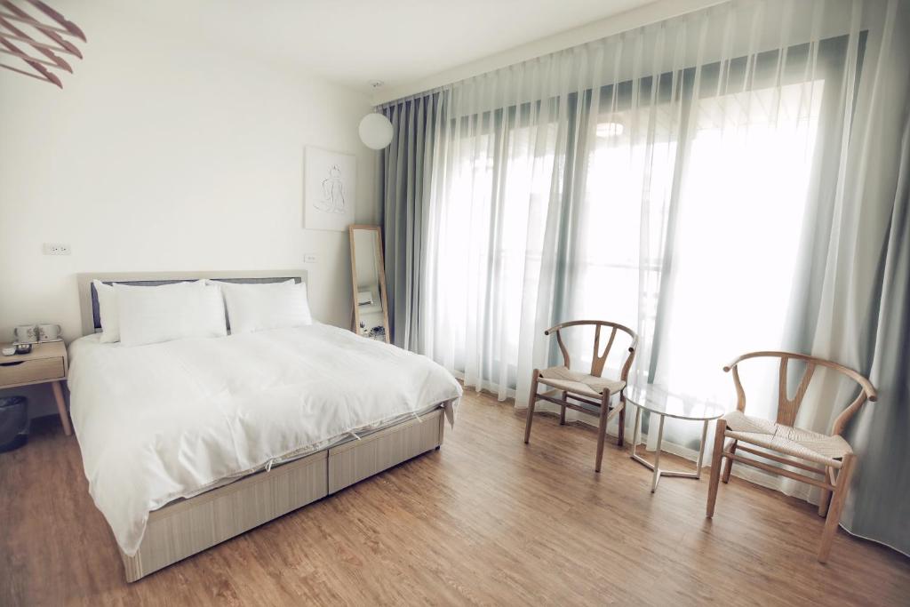 台南66南的卧室配有一张白色大床和两把椅子