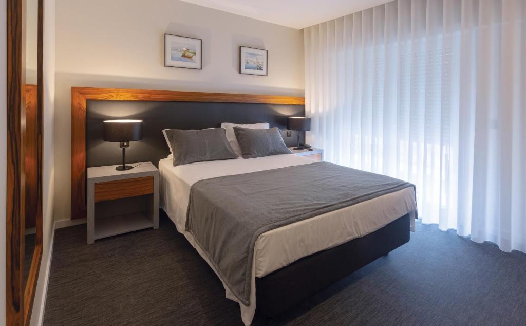 阿威罗Hotel Afonso V & SPA的一间卧室配有一张大床和一个带灯的床头柜