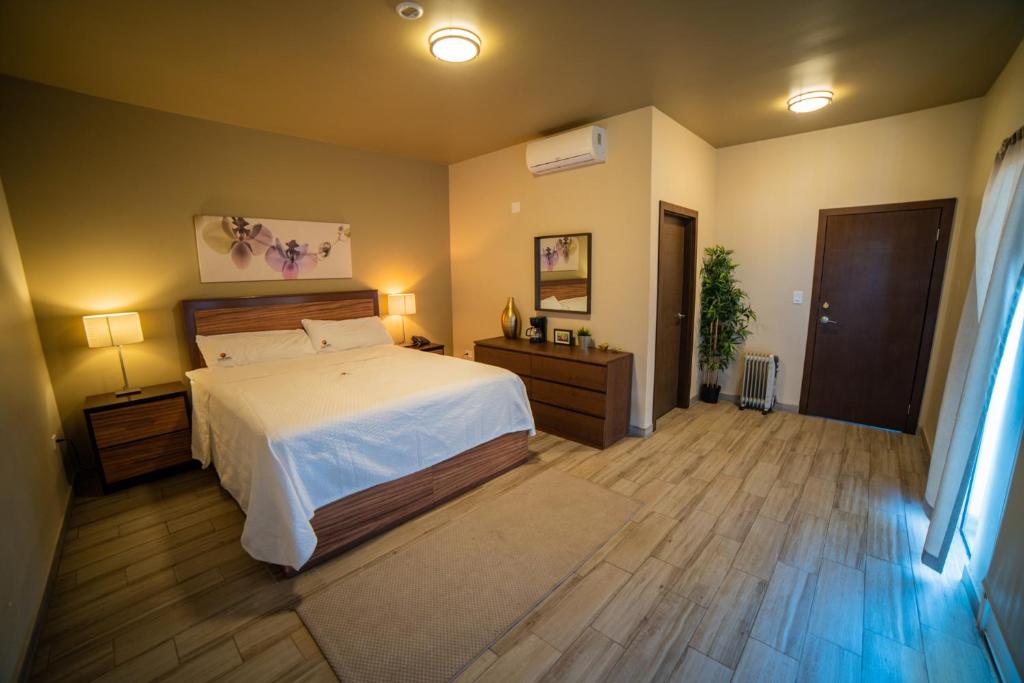 Los AlgodonesCalifornia Comfort & Suites的卧室配有白色的床,铺有木地板