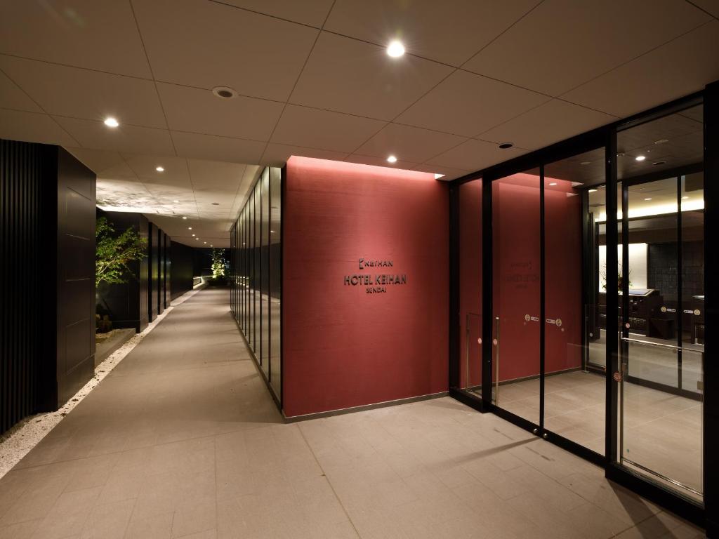 仙台Hotel Keihan Sendai的带有红色墙壁的建筑走廊