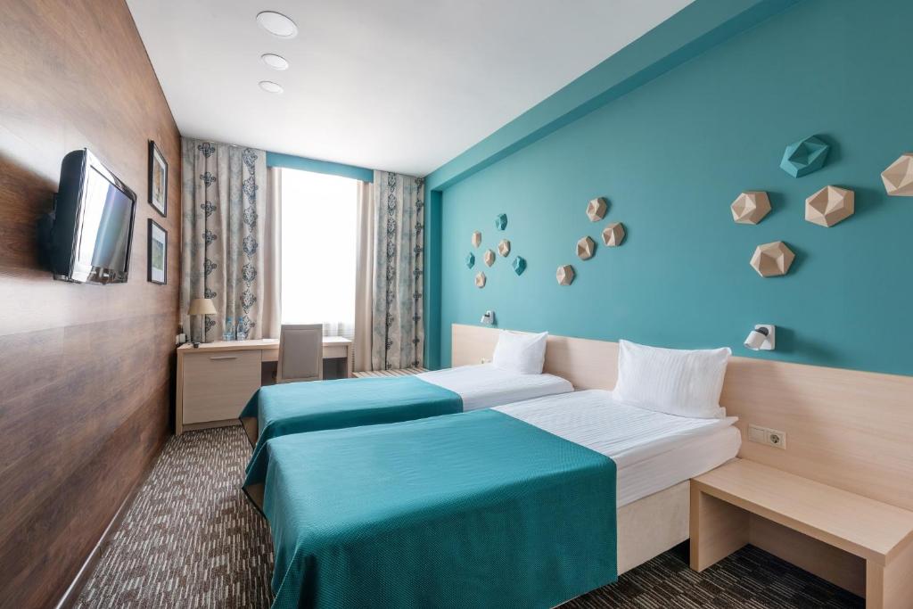 下诺夫哥罗德外交官商务酒店的两张位于酒店客房的床,拥有蓝色的墙壁