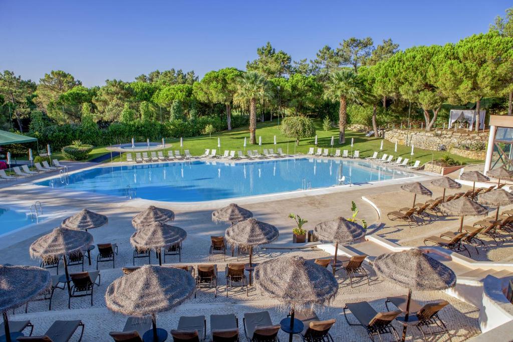 金塔湖Vilar do Golf的一个带遮阳伞和桌椅的大型游泳池