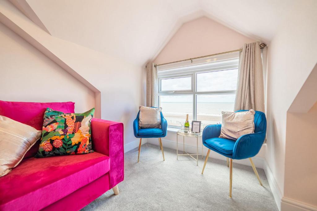 克利夫利斯Charles Alexander Short Stay - Highcliffe Apartments的客厅配有粉红色的沙发和2把蓝色的椅子