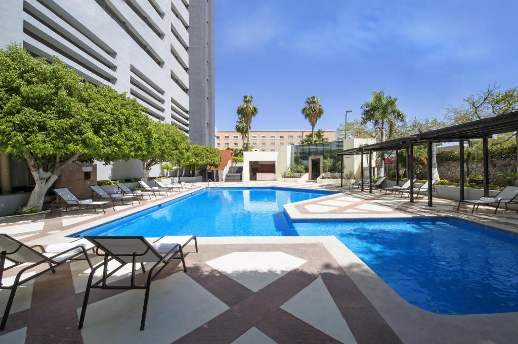 埃莫西约埃莫西美洲嘉年华酒店的一座带椅子的游泳池以及一座建筑