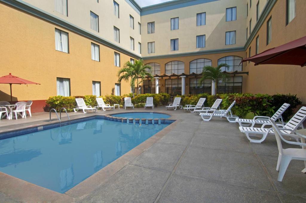 伊达尔戈州波萨里卡波萨里卡嘉年华酒店的一座带游泳池和椅子的酒店和一座建筑