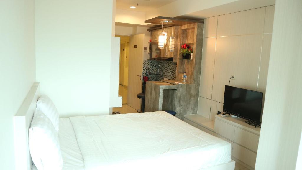 贝克西Apartemen Grand Kamala Lagoon by Cheapinn的卧室配有白色的床和电视。