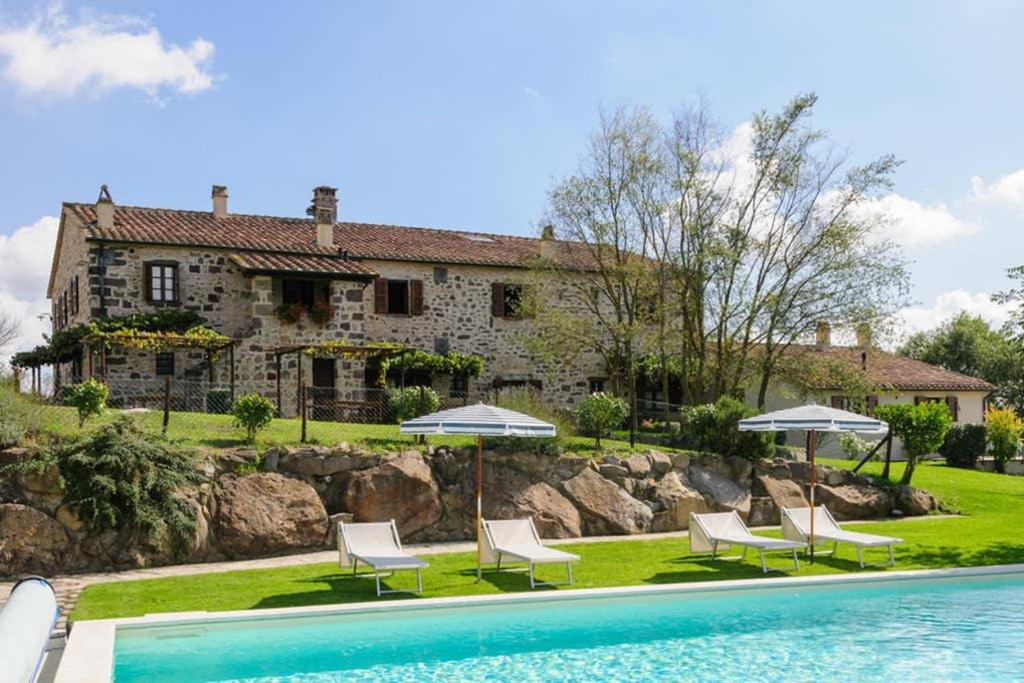 拉迪科法尼Girasole Cottage overlooking the Orcia valley in Tuscany的一座房子,设有一座带椅子和遮阳伞的游泳池