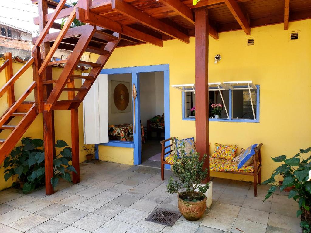 帕拉蒂Pousada Recanto dos Nativo的黄色的房子,设有木楼梯和长凳