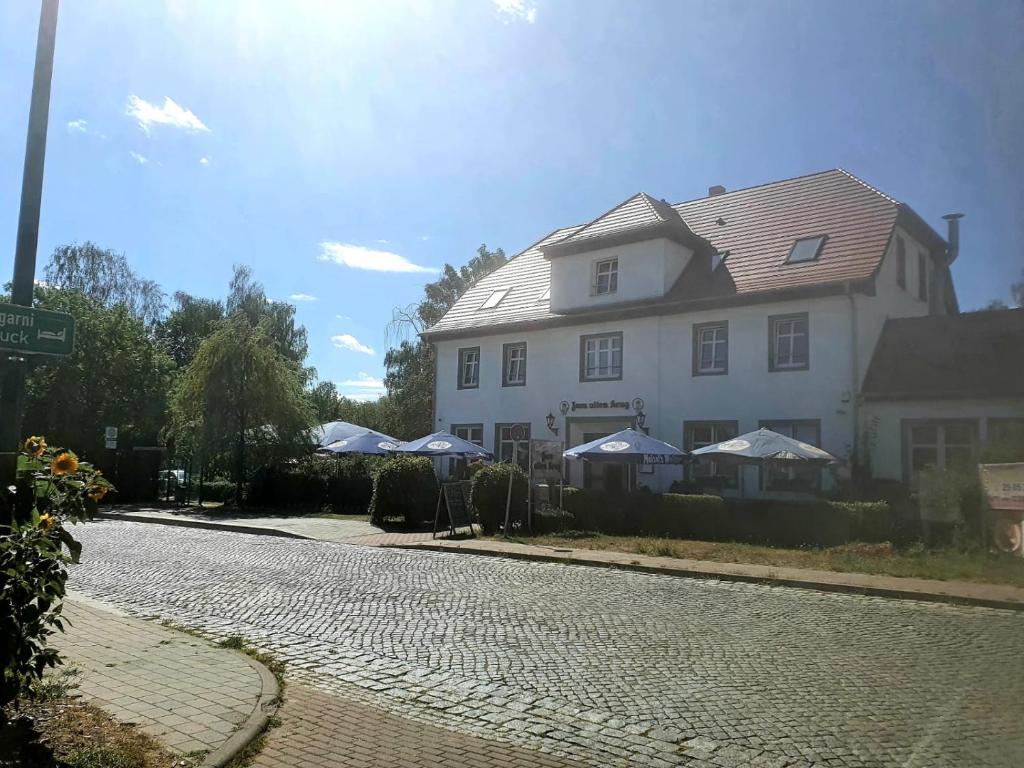波茨坦Landgasthof Alter Krug Potsdam OT Marquardt的路边有遮阳伞的大型白色房屋