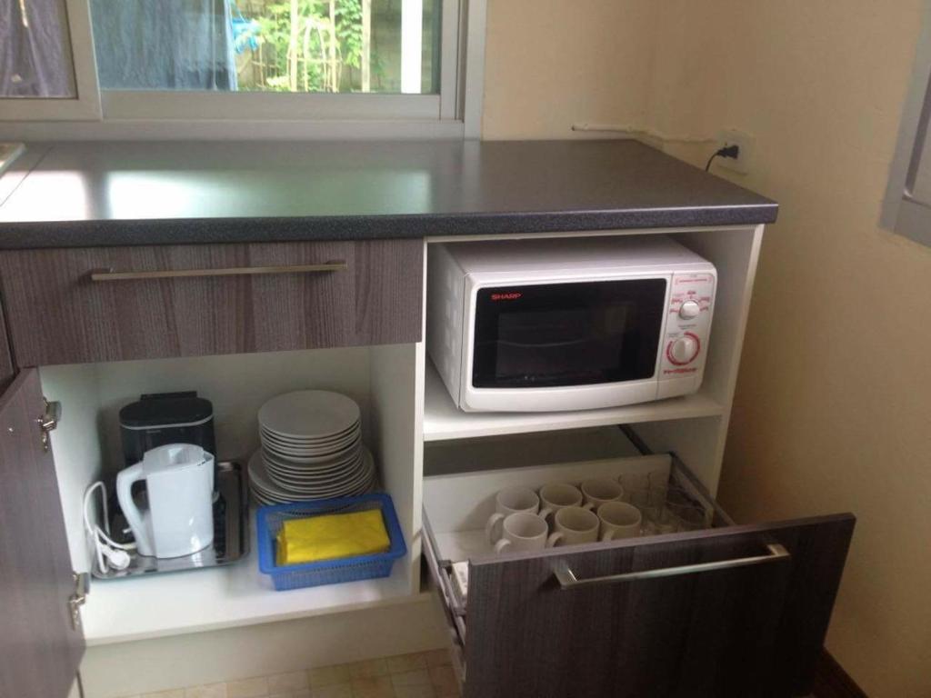 Ban Mae Kon简森之家度假屋的厨房配有微波炉,并配以盘子和盘子