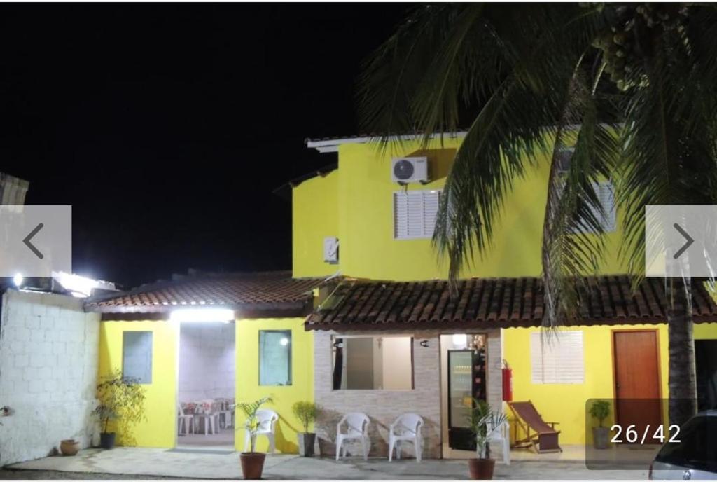 阿帕雷西达Pousada Guadalupe的黄房子,晚上在前面有椅子