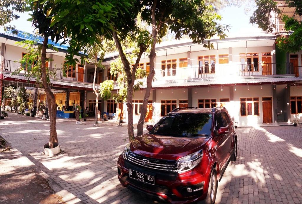 万加普Pondok Wisata dan Restoran Elim的停在大楼前的红色山 ⁇ 