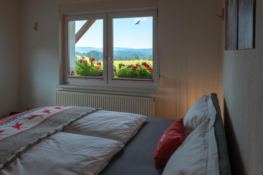 美瑟尔巴赫斯瓦兹姆Ferienwohnung FUCHSBAU im EG des Ferienhauses Falkenhöhe的一间卧室设有一张床和一个鲜花窗口