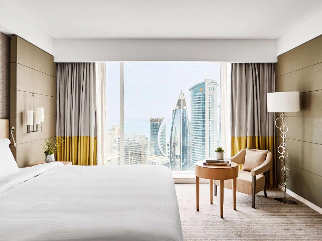 多哈Pullman Doha West Bay的配有一张床、一张书桌和一扇窗户的酒店客房