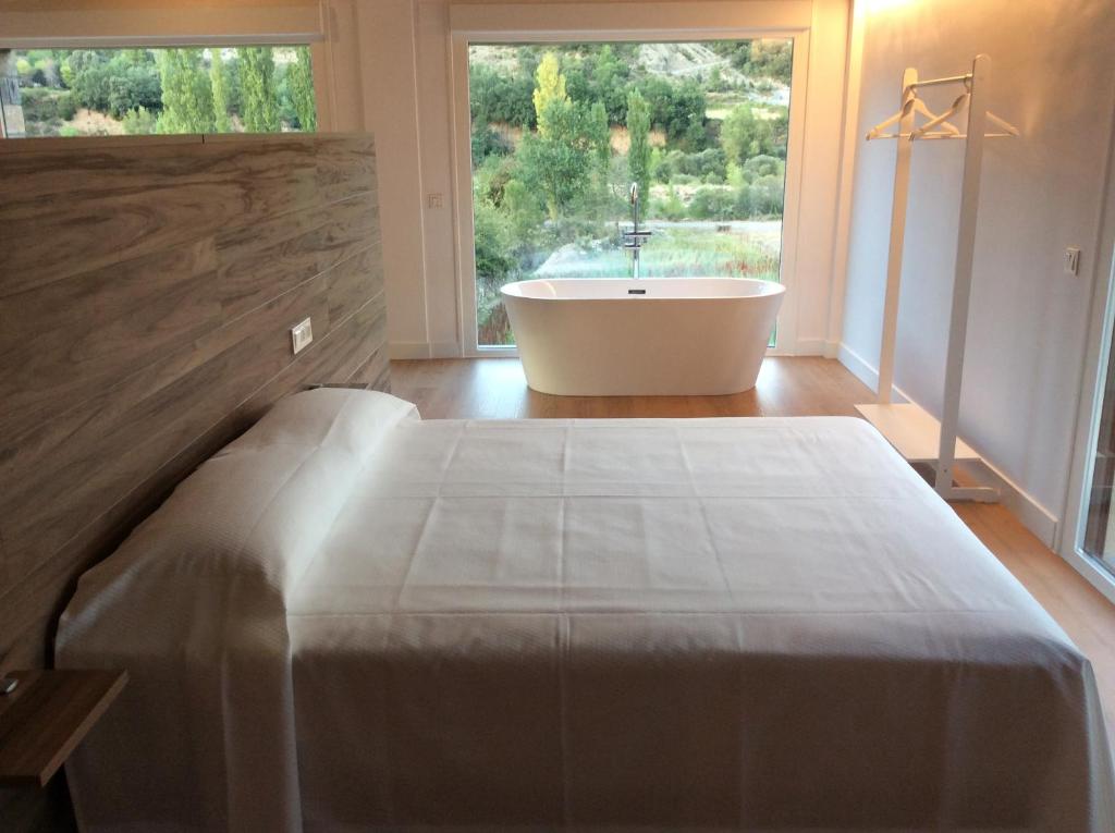 埃斯卡洛纳Huertas de Muro Turismo Rural的一间带浴缸、床和窗户的卧室