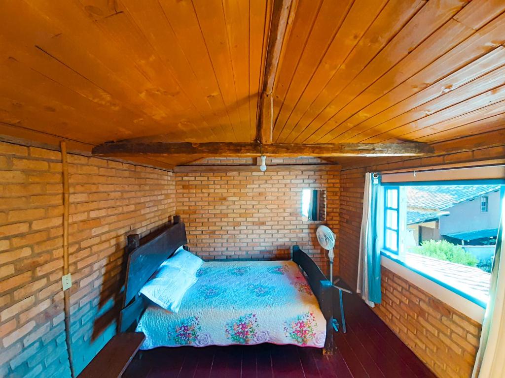 康塞高伊比蒂波卡Chalé da Léia的卧室配有砖墙内的床铺