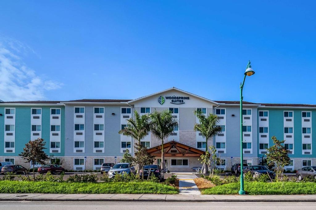 那不勒斯WoodSpring Suites Naples West的一座蓝色的大建筑,汽车停在停车场