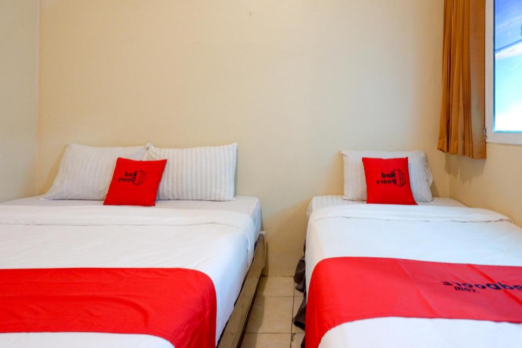 三宝垄RedDoorz @ Jalan Setiabudi Semarang 2的客房内的两张床和红色枕头