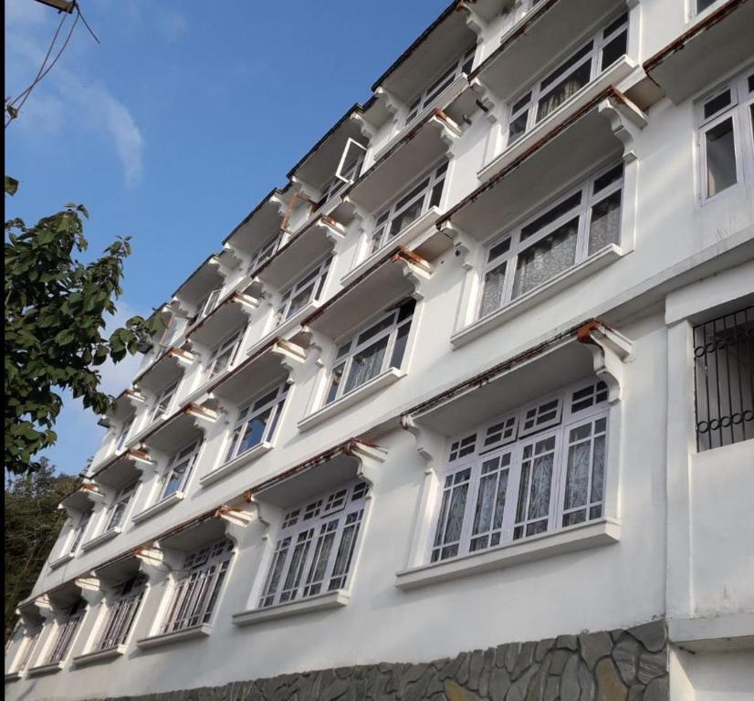 大吉岭Hotel Taktsang Darjeeling的白色的建筑,窗户在建筑的一侧