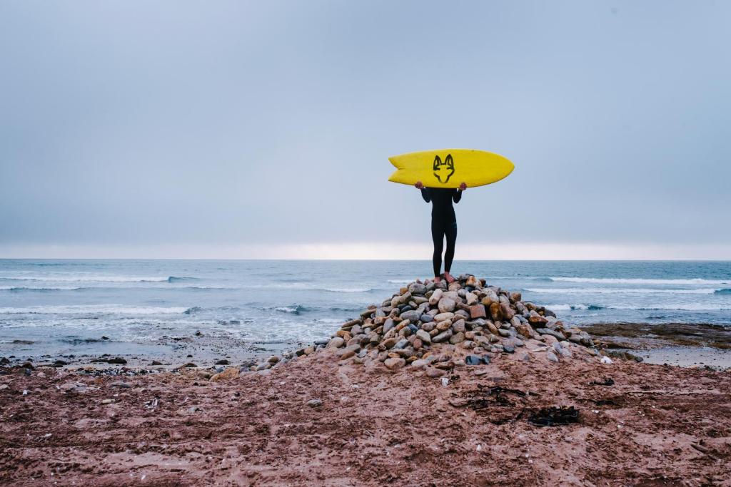 斯瓦科普蒙德Salty Jackal Backpackers & Surf Camp的站在一块石头上,有冲浪板的人