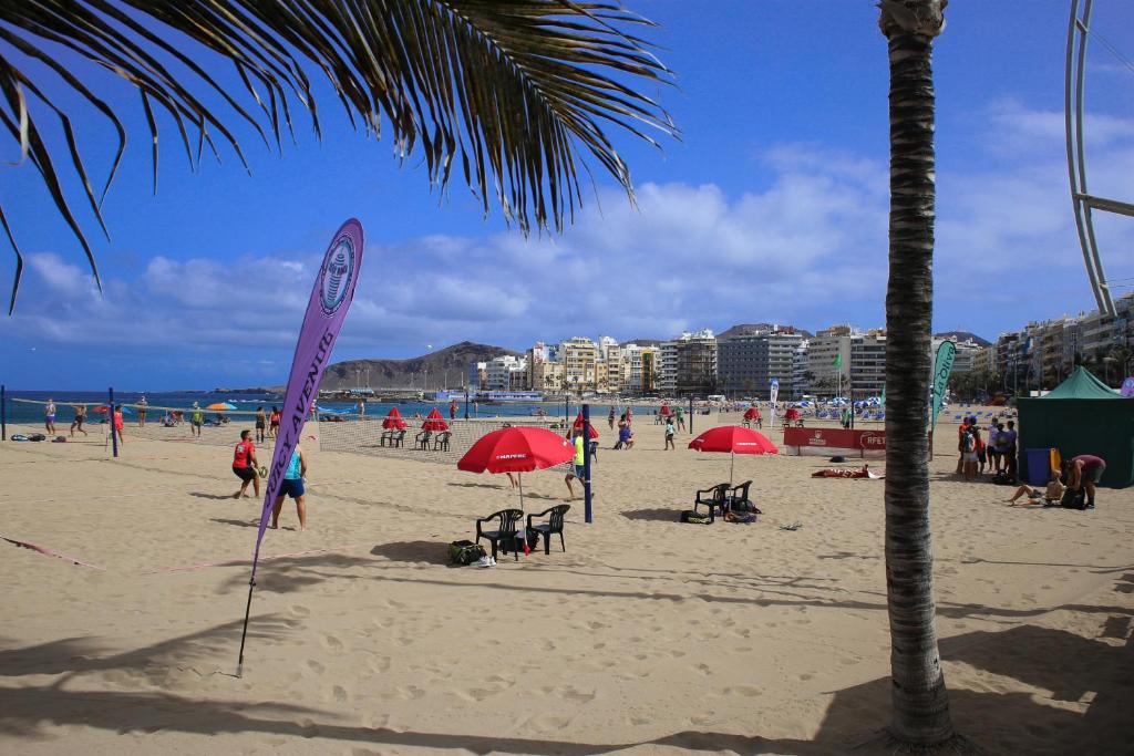 大加那利岛拉斯帕尔马斯Atlantic Apartments的一群人,在沙滩上,用红伞