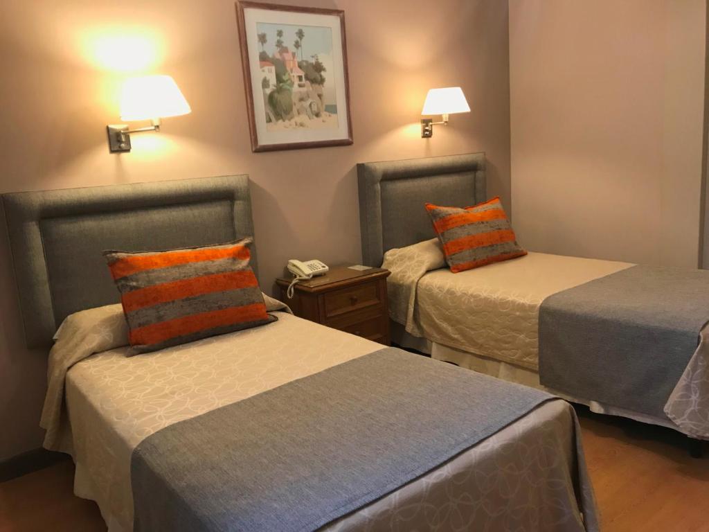 门多萨克丽珑门多萨酒店的酒店客房带两张带橙色和蓝色枕头的床