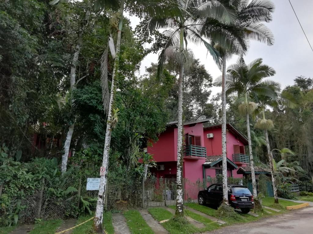 乌巴图巴Villa Félix Suites e Chalés的一座粉红色的房子,前面有一辆汽车