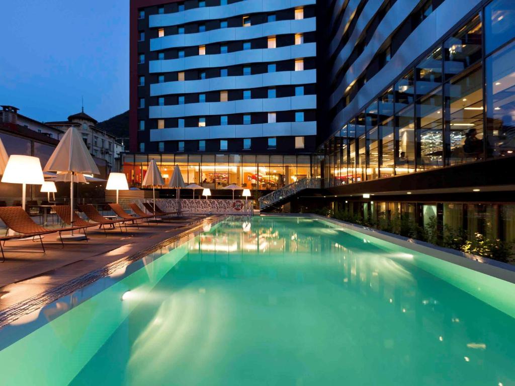 卢加诺诺富特卢加诺天堂酒店 的大楼前的大型游泳池