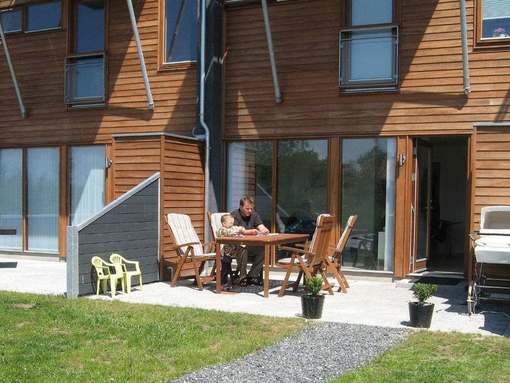 博恩瑟4 person holiday home in Bogense的坐在房子前面桌子上的男人
