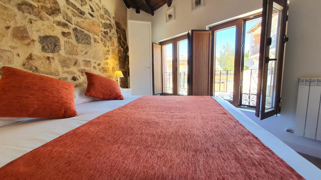 阿维拉Casas del Castillo, 3的一间卧室配有一张大床,上面有红色地毯