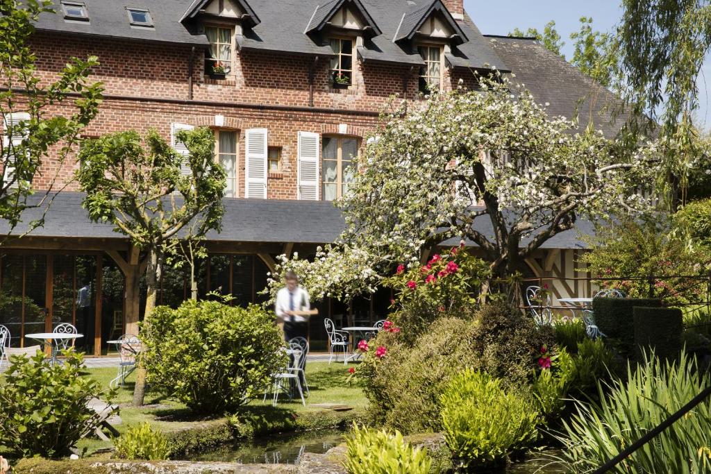 Barneville-la-BertrandAuberge de la Source - Hôtel de Charme, Collection Saint-Siméon的站在建筑物前的人