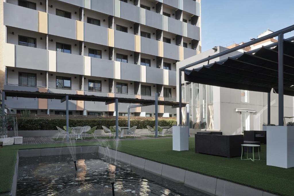 萨拉戈萨萨拉戈萨中心文奇酒店的大楼前有游泳池的酒店