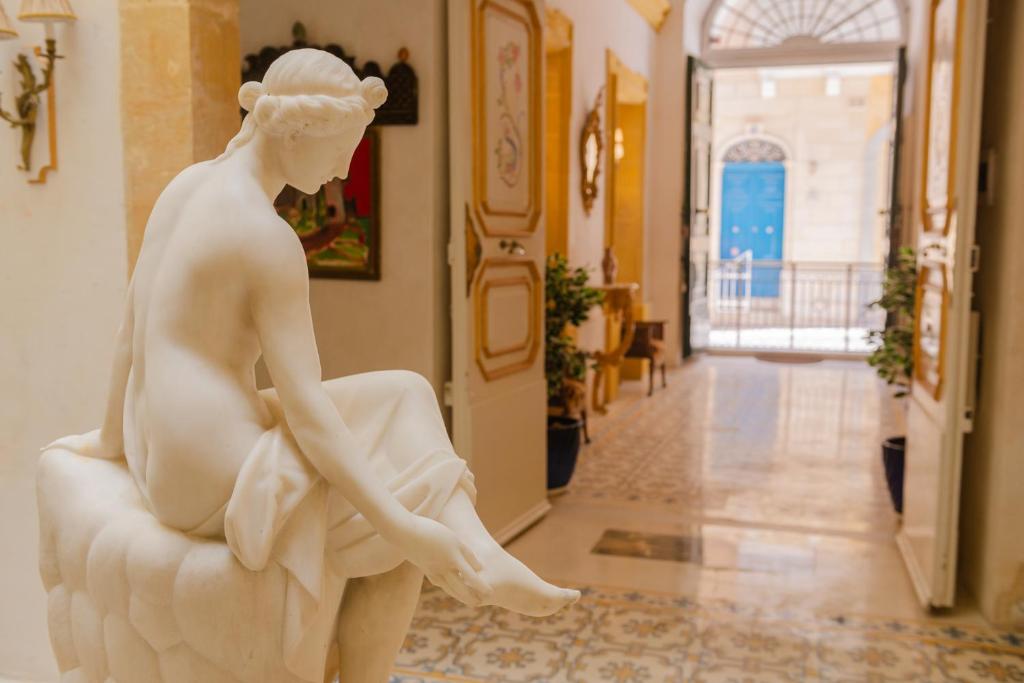瓦莱塔Casa Rocca Piccola B&B的坐在走廊椅子上的女人的雕像