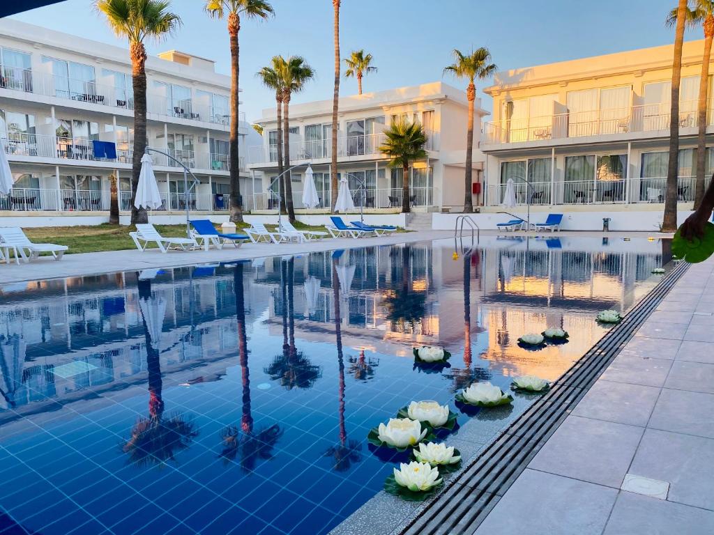拉纳卡Lysithea Hotel的一座游泳池,里面摆放着椅子和棕榈树