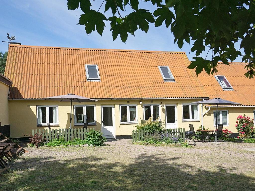 斯瓦讷克Two-Bedroom Holiday home in Svaneke 4的一座黄色的房子,有橙色的屋顶和院子