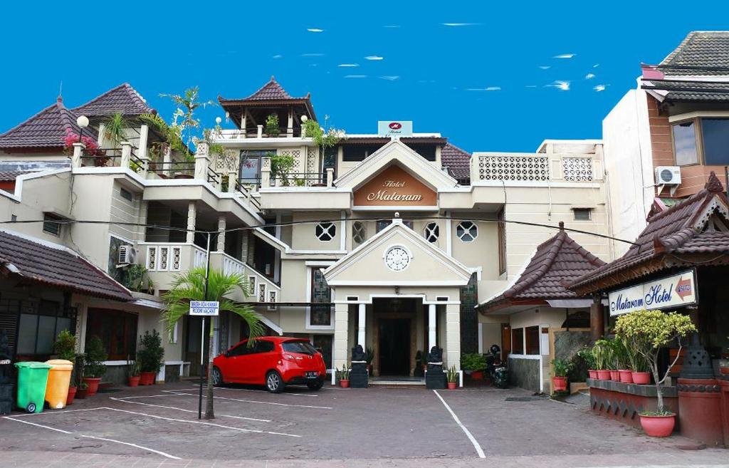 日惹Hotel Mataram Malioboro的停在大楼前的红色汽车