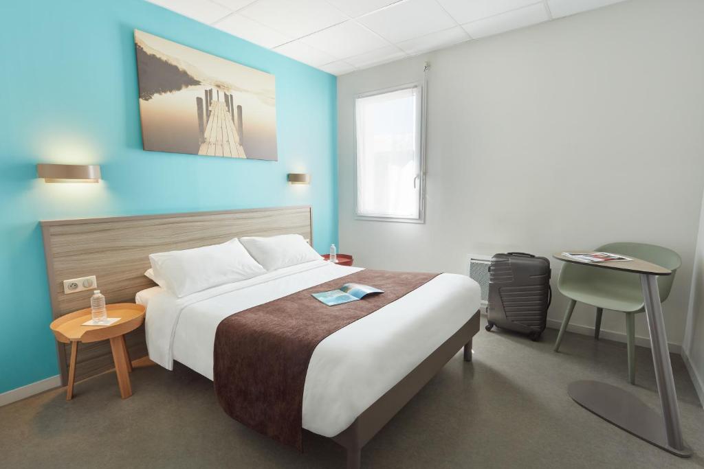 RuaudinAshley Hotel Le Mans Sud的一间卧室配有一张大床和一张桌子