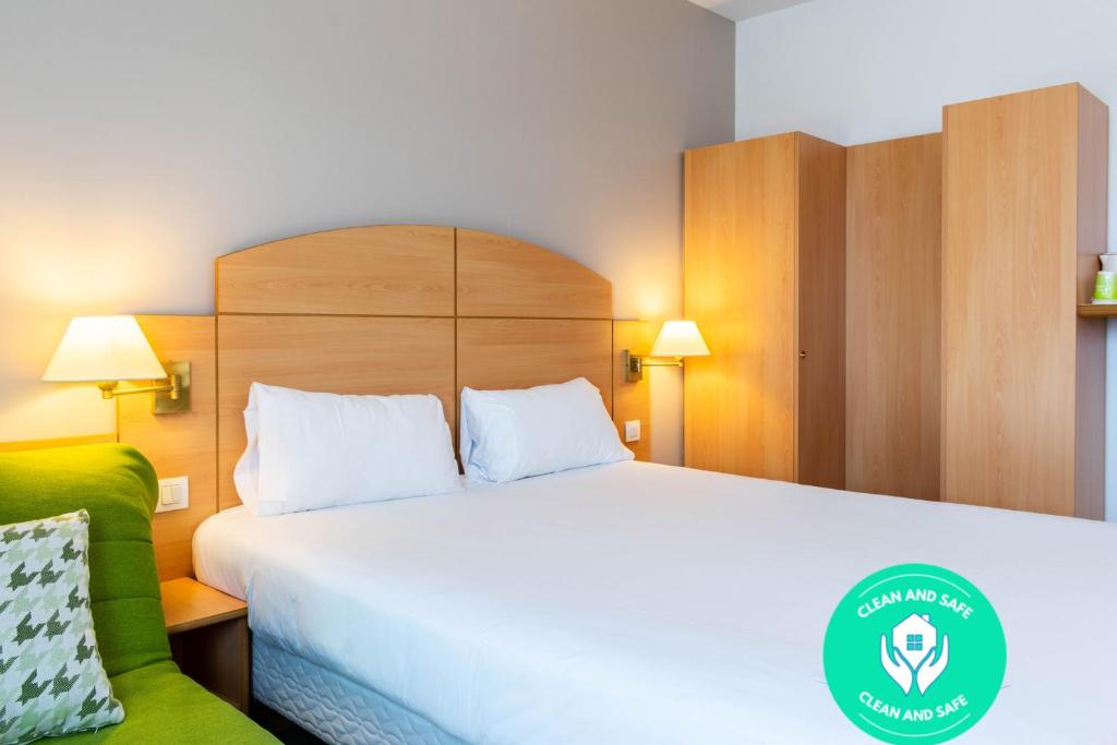 阿尔卡拉德荷那利斯Travelodge Madrid Alcalá de Henares的酒店客房,设有一张床铺和一张绿色沙发