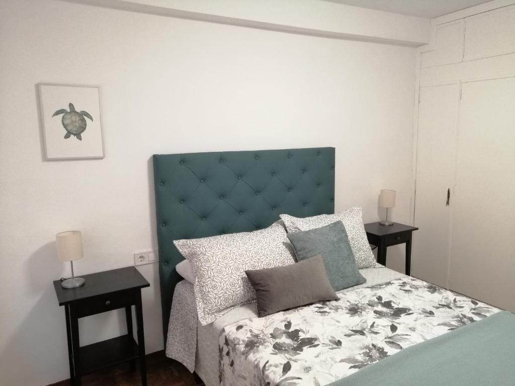 希洪Apartamento Quety Gijón的一间卧室配有一张带蓝色床头板和枕头的床。