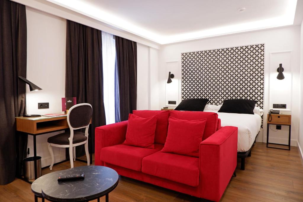 巴利亚多利德Hotel Colón Plaza的酒店客房配有红色的沙发和床。