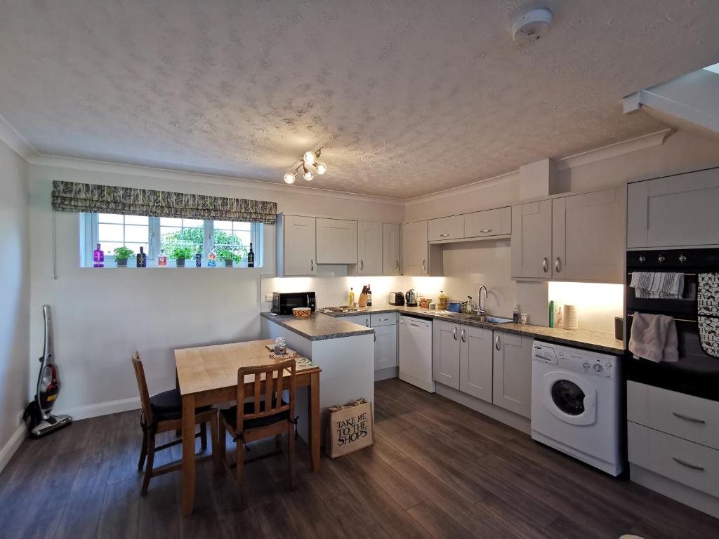 昂德尔Chapel Cottage的厨房配有白色橱柜和桌椅