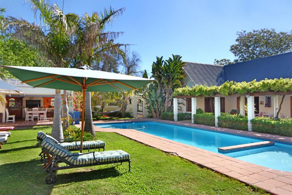 斯泰伦博斯Kleinbosch Lodge的一座房子旁的游泳池,配有两把椅子和一把遮阳伞