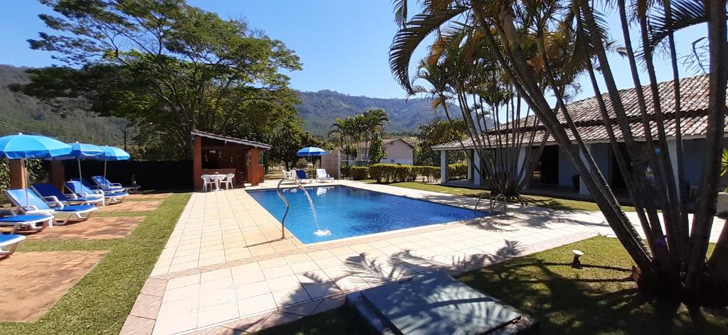 圣代佩德罗Hotel - Pousada 3 Marias的庭院内带椅子和遮阳伞的游泳池