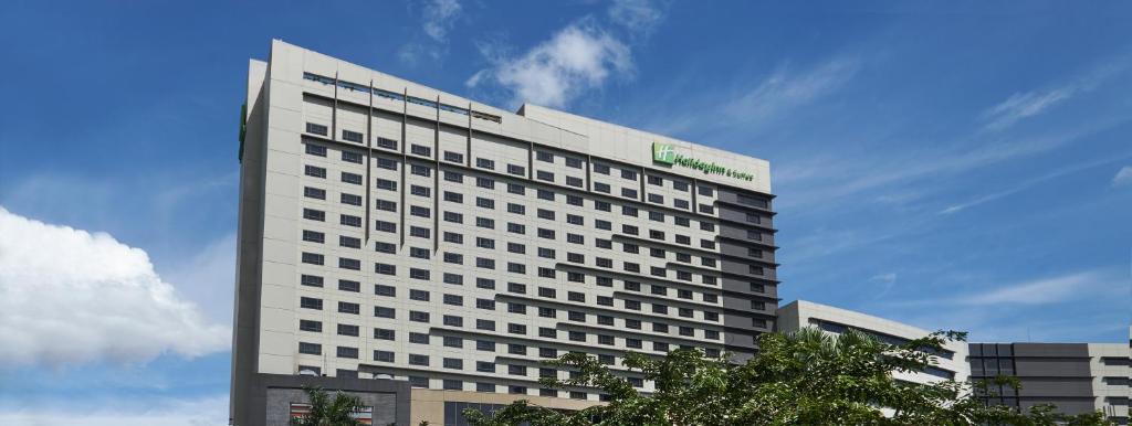马尼拉Holiday Inn & Suites Makati, an IHG Hotel的上面有绿色标志的高大的白色建筑