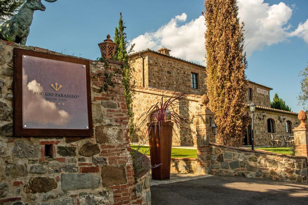 MontefollonicoPoggio Paradiso Resort & Spa的石头建筑前的标志